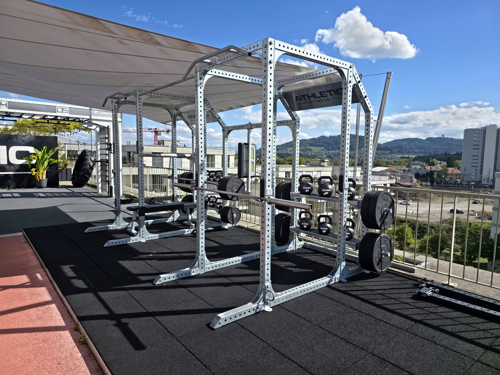 Salle de musculation en plein air sur un toit-terrasse, racks et disques installés par sc-fitnessprojects
